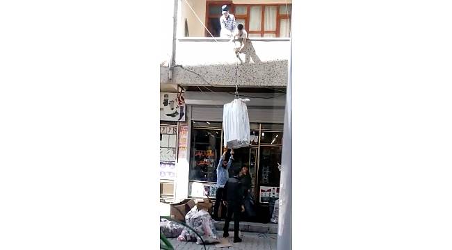 Çuvala doldurulan eşyaları balkondan iple taşıdılar